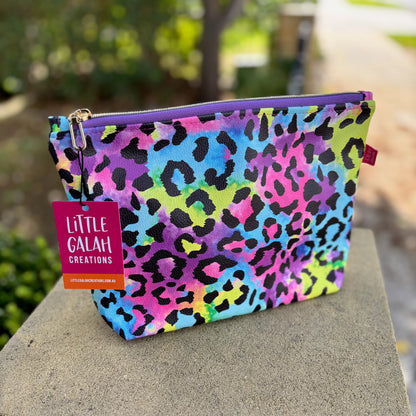 Colorful leopard print pouch with a 'Little Galah Creations' tag on a stone surface.