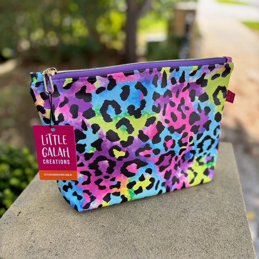 Colorful leopard print pouch with a 'Little Galah Creations' tag on a stone surface.