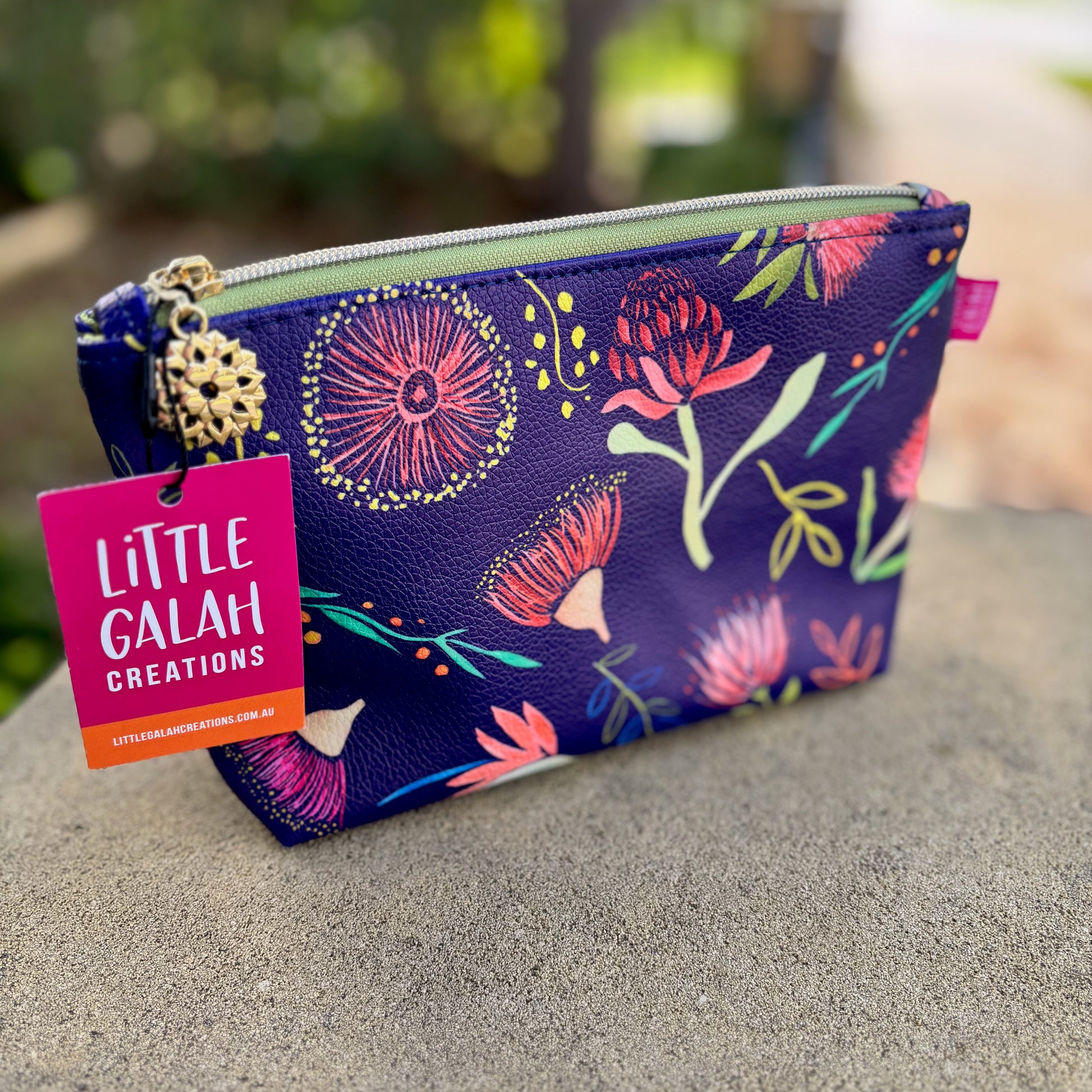 Floral-patterned pouch with 'Little Galah Creations' tag on a blurred natural background